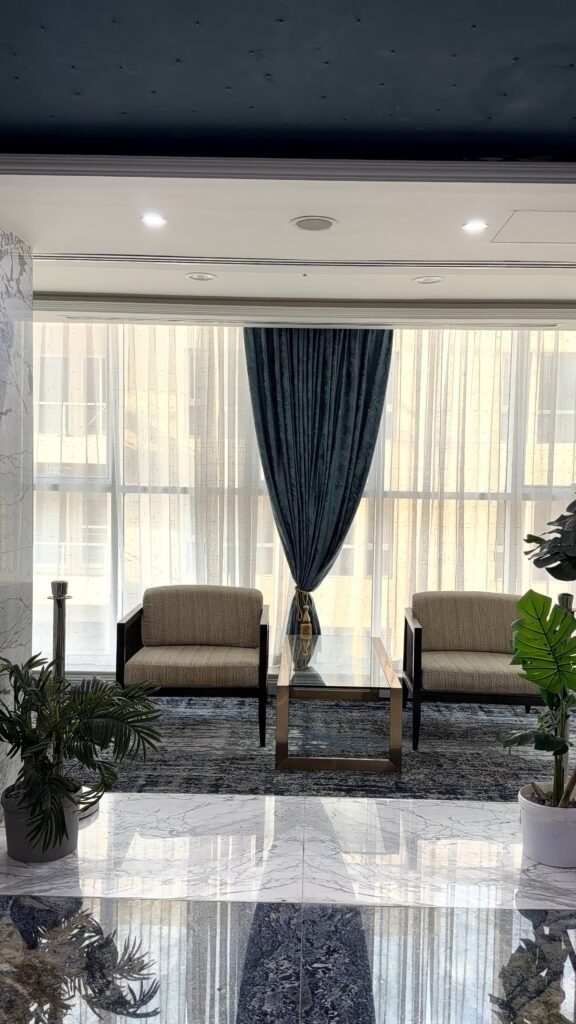 A stylish waiting area featuring modern furniture, blue drapes, and natural light.