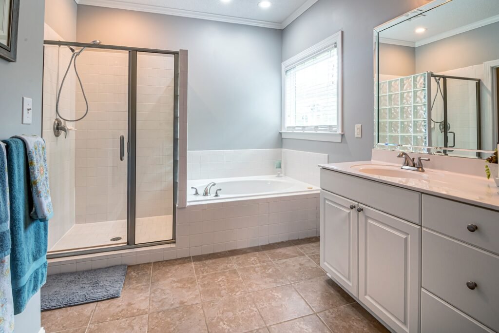 Bright modern bathroom featuring a sleek shower, bathtub, and white cabinets for a clean aesthetic.